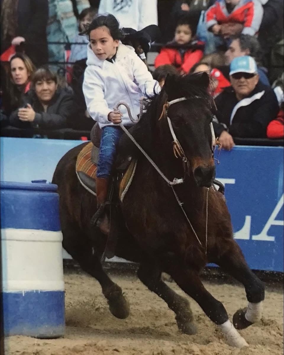 Una chica de la familia doblando un barril con su caballo zaino